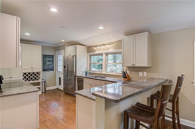 kitchen with stone counters, a peninsula, white cabinets, black dishwasher, and stainless steel fridge with ice dispenser