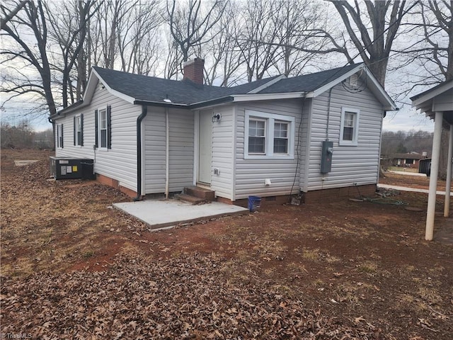 back of house featuring entry steps, cooling unit, a shingled roof, crawl space, and a chimney