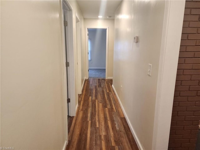 corridor with baseboards and dark wood finished floors