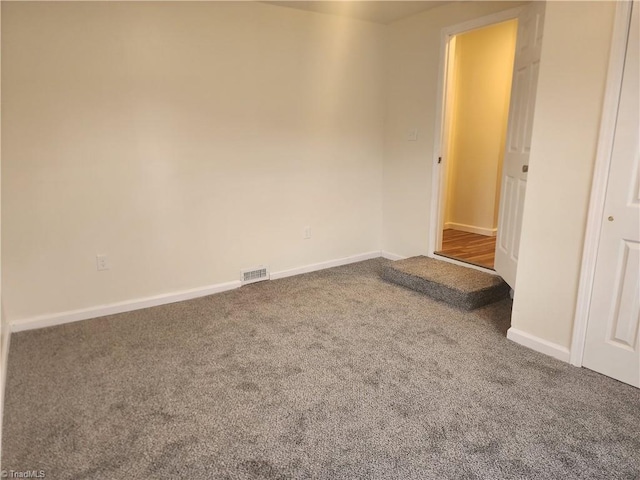 empty room with carpet, visible vents, and baseboards