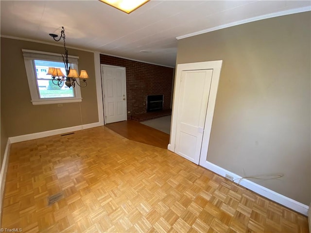 interior space with brick wall, a fireplace, parquet flooring, crown molding, and an inviting chandelier