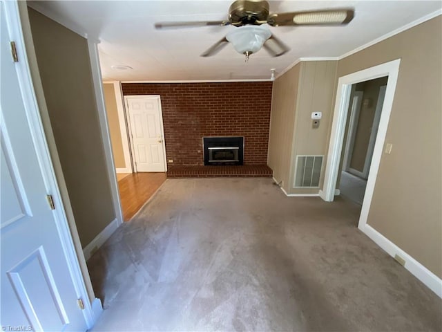 unfurnished living room with a brick fireplace, brick wall, crown molding, carpet flooring, and ceiling fan