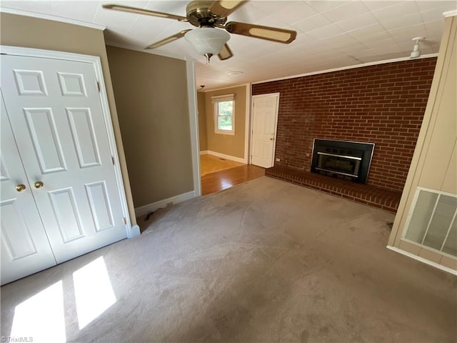 unfurnished living room featuring light colored carpet, a fireplace, ornamental molding, ceiling fan, and brick wall