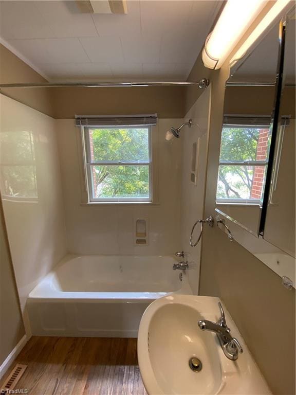 bathroom featuring hardwood / wood-style floors,  shower combination, and a wealth of natural light