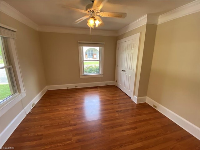 empty room with ornamental molding, dark wood-type flooring, and ceiling fan