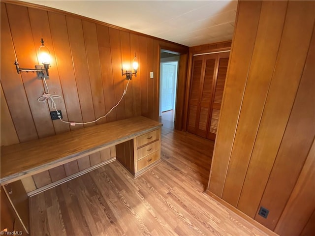 hallway featuring light wood-type flooring and wood walls