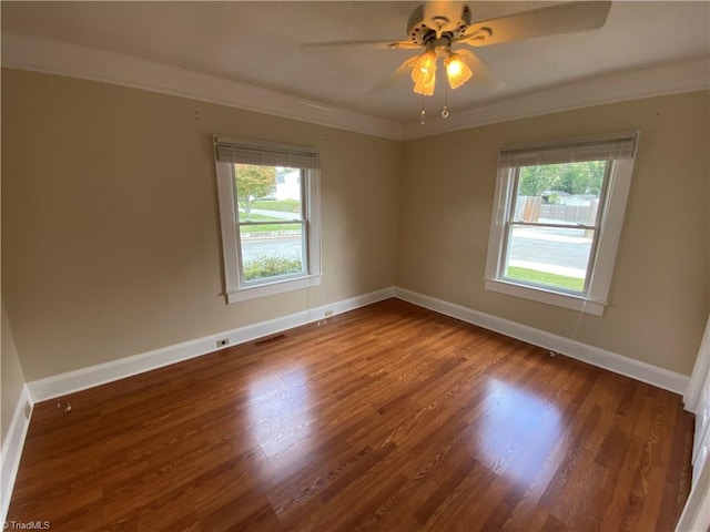 spare room featuring a healthy amount of sunlight, ornamental molding, dark hardwood / wood-style flooring, and ceiling fan