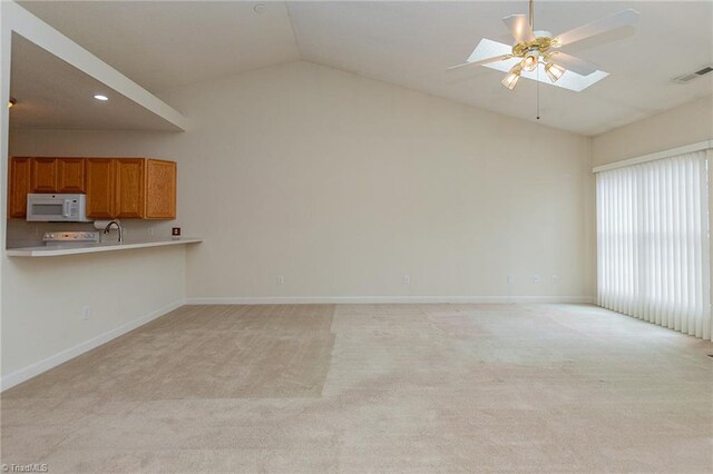 unfurnished living room with light carpet, visible vents, a skylight, and baseboards