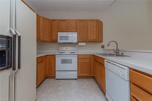 kitchen featuring white appliances, light countertops, and a sink