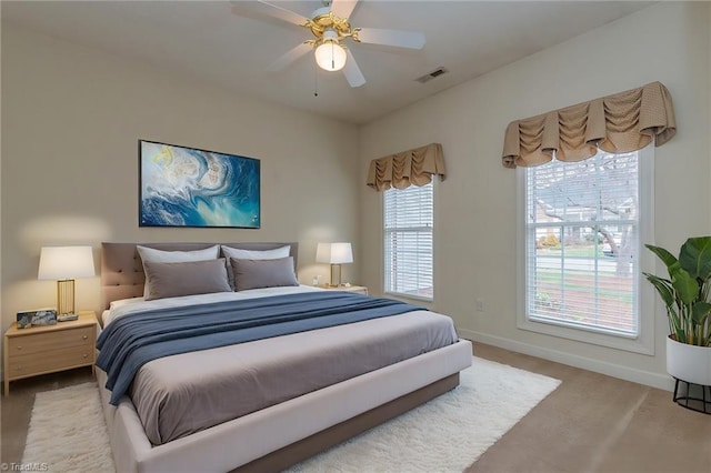 carpeted bedroom with visible vents, baseboards, and a ceiling fan