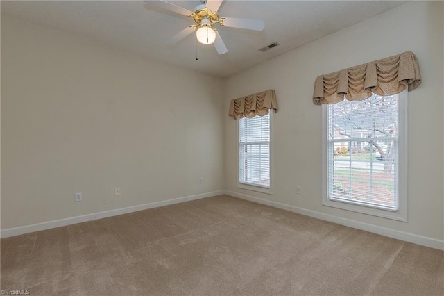 spare room with visible vents, light colored carpet, a ceiling fan, and baseboards