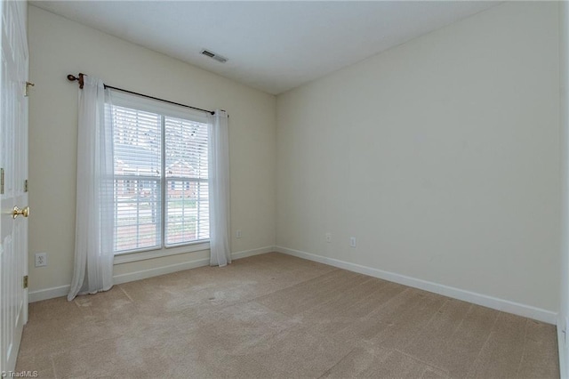 empty room featuring light carpet, visible vents, and baseboards