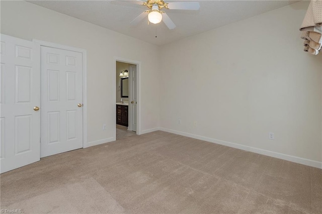 unfurnished bedroom featuring baseboards, light carpet, a ceiling fan, and ensuite bathroom