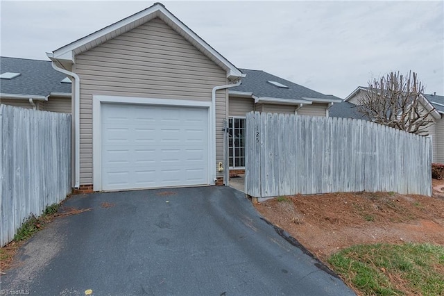 view of front of house with a garage, fence, and aphalt driveway