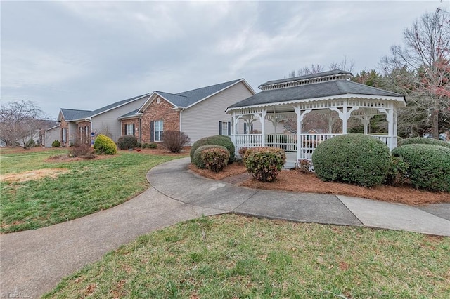 view of front of home with a gazebo, brick siding, and a front yard