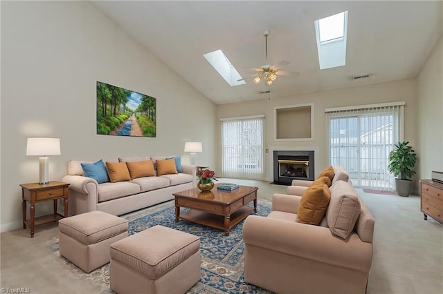 living room featuring a fireplace with flush hearth, light colored carpet, a skylight, and high vaulted ceiling