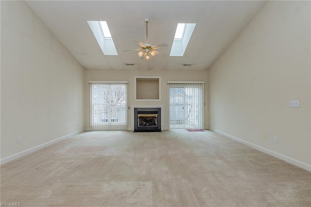 unfurnished living room with baseboards, a fireplace with flush hearth, ceiling fan, and carpet flooring