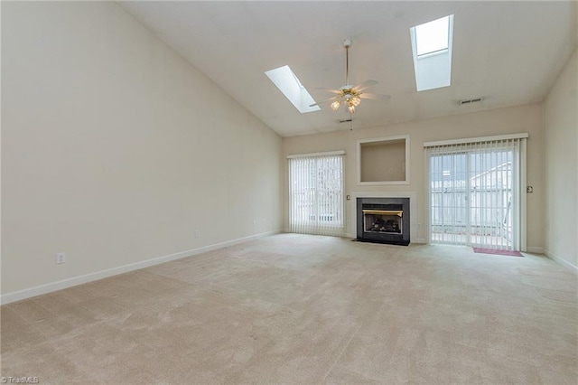 unfurnished living room with a healthy amount of sunlight, a fireplace, a skylight, and carpet floors