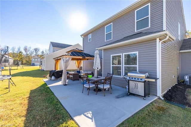 rear view of property featuring an outdoor living space, a lawn, a patio area, a gazebo, and a trampoline