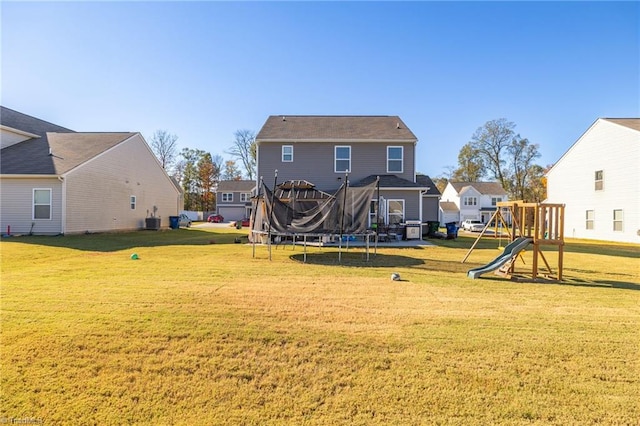 back of property featuring a playground, a yard, and a trampoline