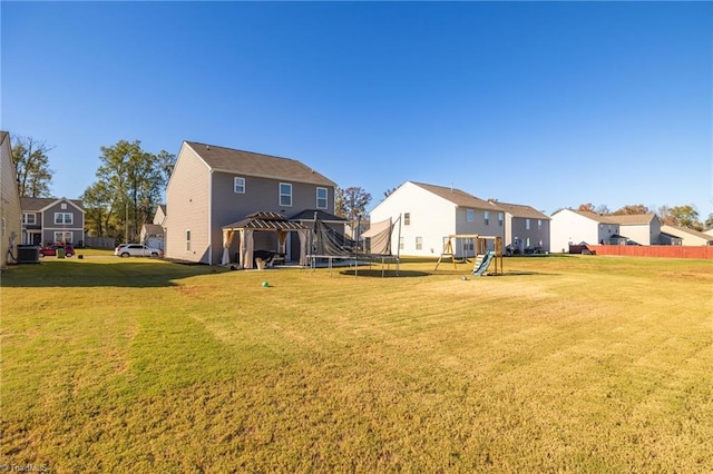 rear view of house featuring a playground, a yard, central AC unit, and a trampoline