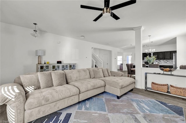 living room featuring ornate columns, wood-type flooring, and ceiling fan with notable chandelier