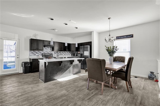 kitchen featuring a kitchen breakfast bar, light hardwood / wood-style flooring, an island with sink, pendant lighting, and appliances with stainless steel finishes