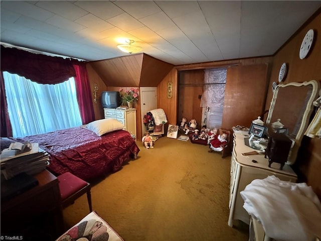 carpeted bedroom with lofted ceiling and wood walls