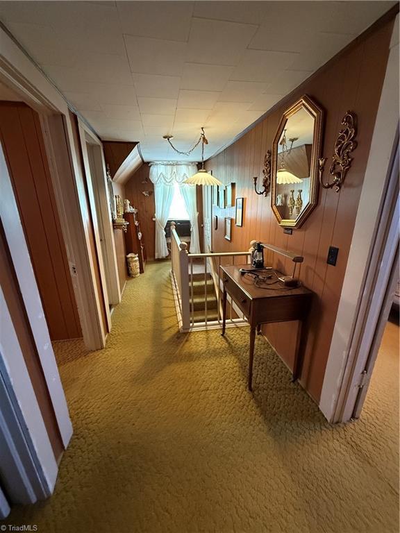 corridor with light colored carpet and wood walls