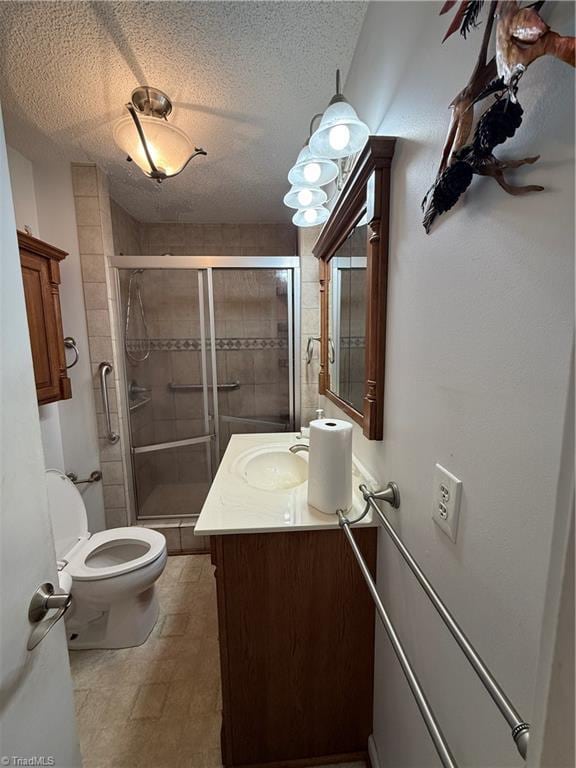 bathroom featuring vanity, toilet, a textured ceiling, and walk in shower