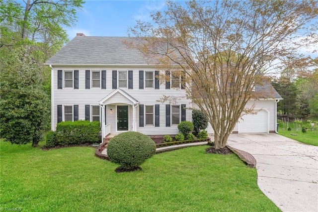 colonial inspired home with concrete driveway, an attached garage, and a front lawn