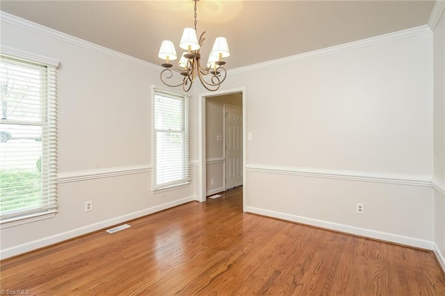unfurnished room with ornamental molding, visible vents, a chandelier, wood finished floors, and baseboards