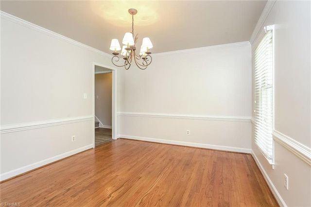 unfurnished room with ornamental molding, baseboards, a chandelier, and wood finished floors
