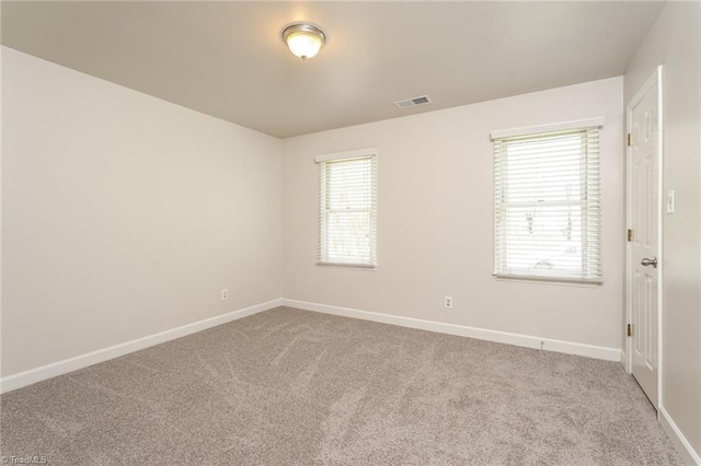 carpeted spare room with visible vents and baseboards