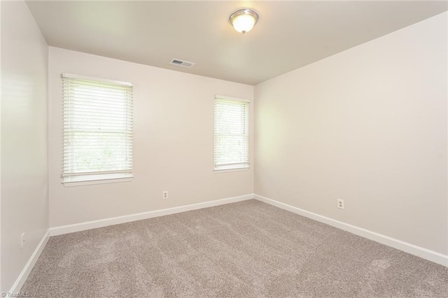 empty room featuring visible vents, carpet flooring, baseboards, and plenty of natural light