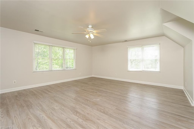 spare room with light wood-type flooring, visible vents, a ceiling fan, and plenty of natural light