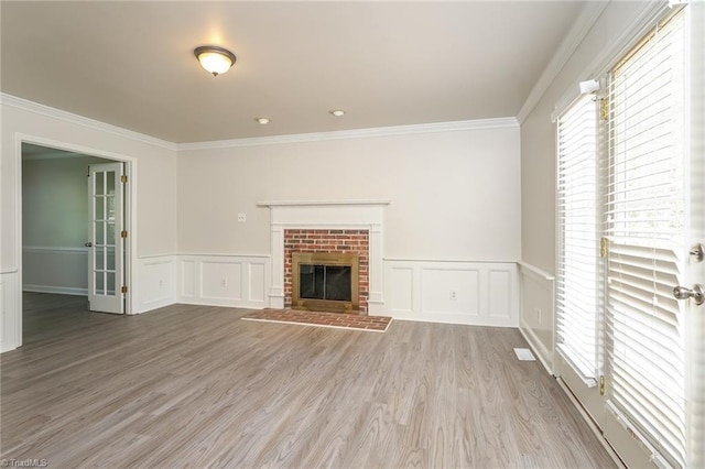 unfurnished living room with a decorative wall, wood finished floors, wainscoting, and crown molding