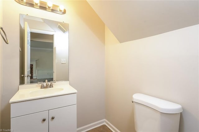 half bath with toilet, vanity, baseboards, and visible vents