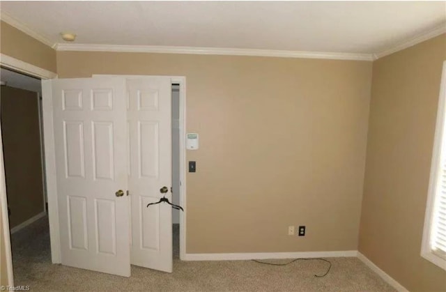 spare room with crown molding, baseboards, and light carpet