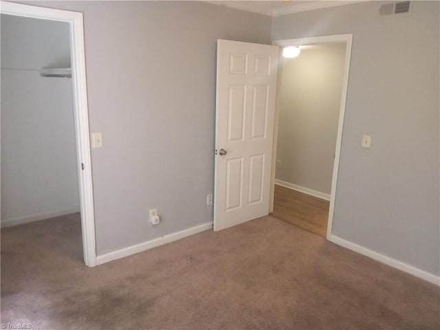 unfurnished bedroom featuring carpet, visible vents, baseboards, and a closet