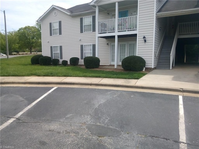view of property featuring stairway and uncovered parking