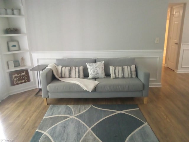 living area featuring a wainscoted wall, built in features, and wood finished floors