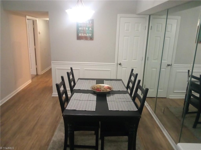 dining area featuring a decorative wall, dark wood-style floors, and baseboards