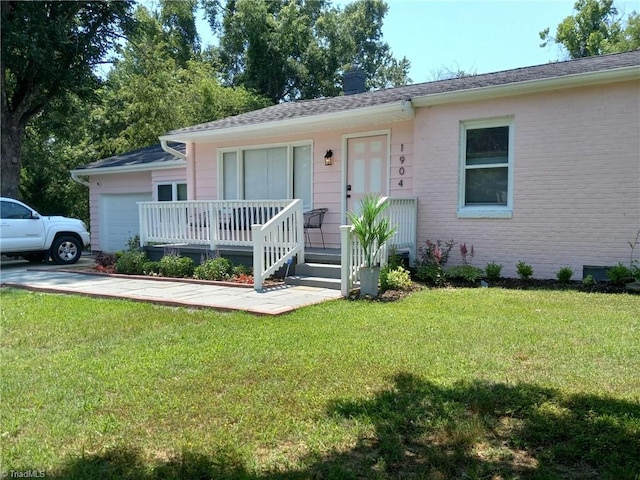 single story home with an attached garage, brick siding, a chimney, and a front yard