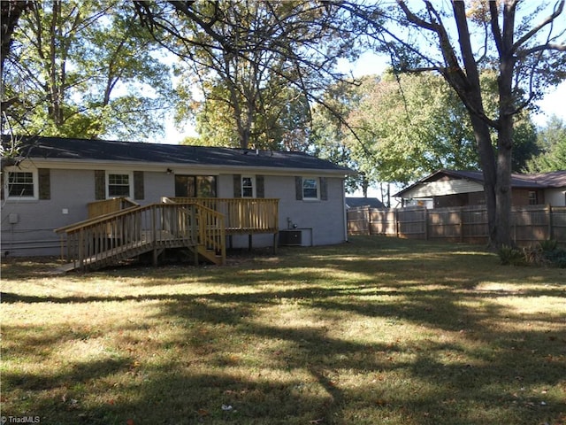 back of property with a deck and a lawn