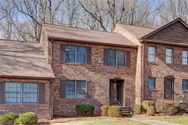 view of front facade with brick siding and a shingled roof