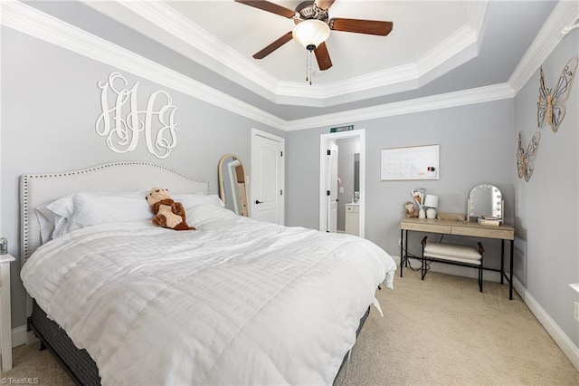 carpeted bedroom with ceiling fan, crown molding, a raised ceiling, baseboards, and ensuite bath