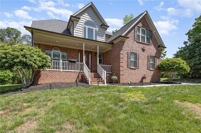 view of front of house with a porch, brick siding, roof with shingles, and a front yard