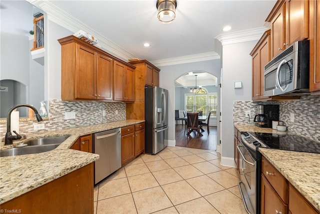 kitchen with light stone counters, a sink, arched walkways, stainless steel appliances, and light tile patterned floors
