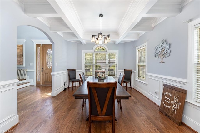 dining space with arched walkways, beamed ceiling, wood finished floors, and a decorative wall